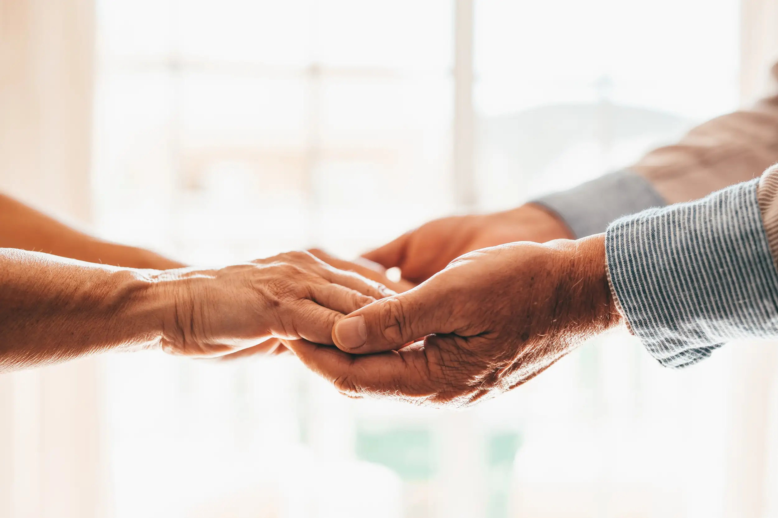 A closeup of an elderly couple holding each other's hands.