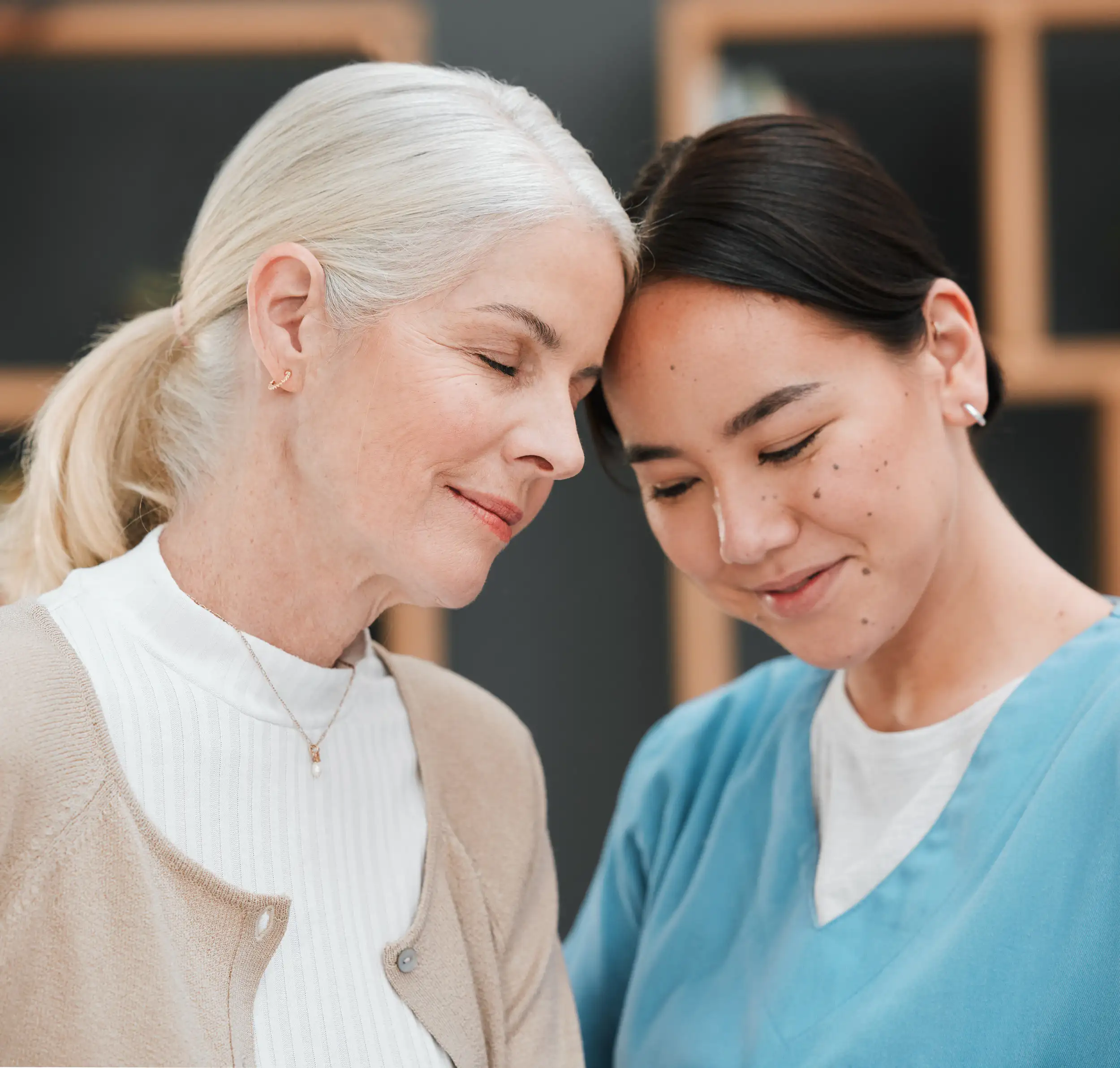 A friendship of a caregiver and an old woman touching their heads as a sign of love.